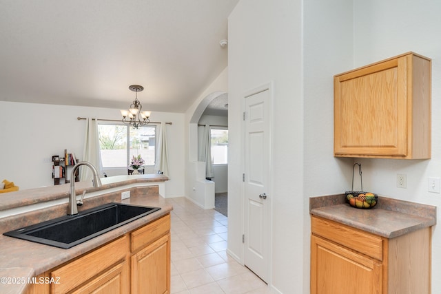 kitchen with light brown cabinetry, arched walkways, a sink, light tile patterned floors, and an inviting chandelier