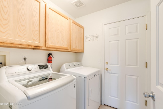 washroom featuring visible vents, cabinet space, and washing machine and clothes dryer