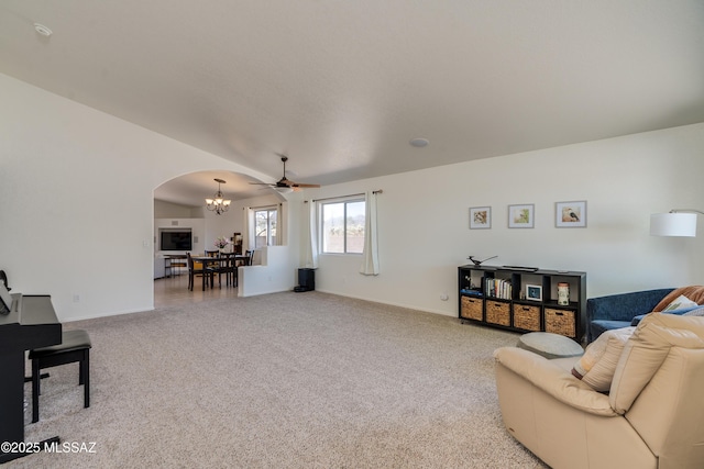 living area with carpet floors, arched walkways, baseboards, and ceiling fan with notable chandelier