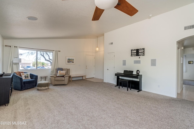 living area featuring ceiling fan, light colored carpet, arched walkways, lofted ceiling, and visible vents