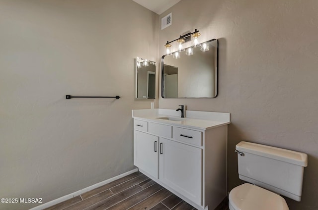 9290 N Jessy Ln, Tucson, AZ 85742 - bathroom featuring wood finished floors, toilet, vanity, baseboards, and visible vents