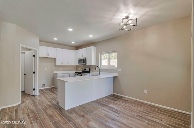 9290 N Jessy Ln, Tucson, AZ 85742 - kitchen with appliances with stainless steel finishes, a sink, baseboards, light wood-type flooring, and a peninsula