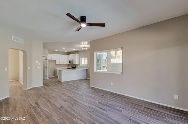 9290 N Jessy Ln, Tucson, AZ 85742 - unfurnished living room featuring visible vents, light wood-type flooring, a ceiling fan, and baseboards