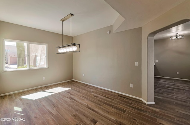 9290 N Jessy Ln, Tucson, AZ 85742 - unfurnished dining area with dark wood-style floors, arched walkways, a chandelier, and baseboards