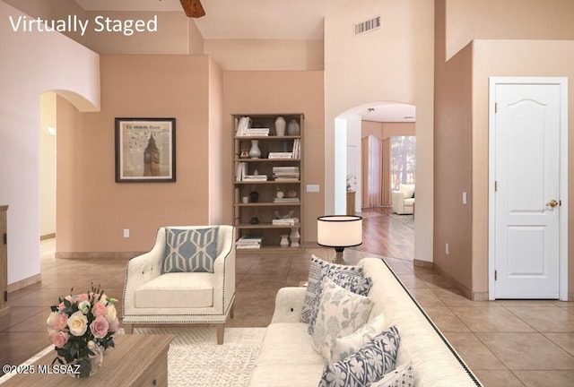 2377 W Catalina View Dr, Tucson, AZ 85742 - living room featuring arched walkways, light tile patterned floors, baseboards, and a towering ceiling