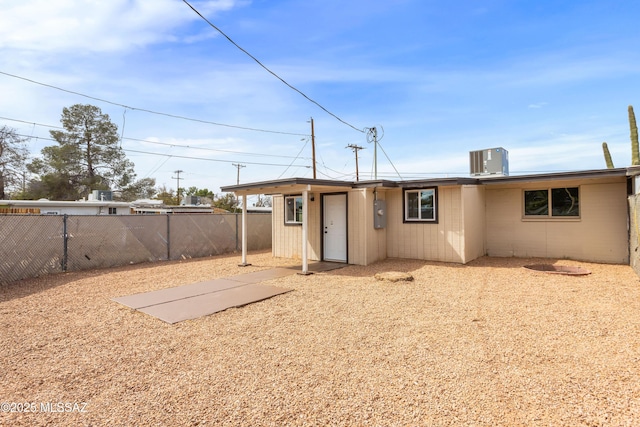 rear view of house with fence, cooling unit, and concrete block siding
