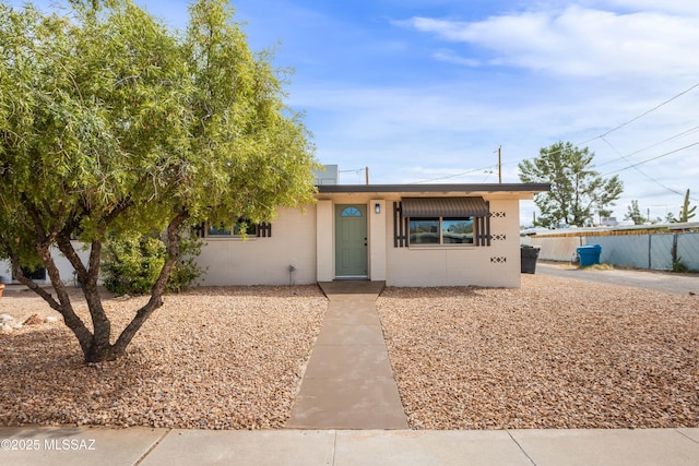 ranch-style house with fence and concrete block siding
