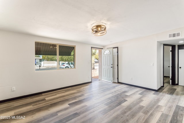empty room featuring baseboards, visible vents, and wood finished floors