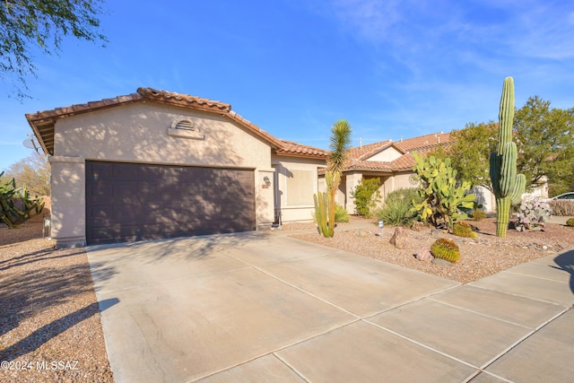 mediterranean / spanish home with a tile roof, driveway, a garage, and stucco siding