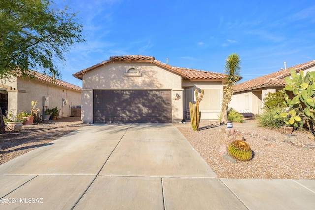mediterranean / spanish-style home with a tiled roof, stucco siding, concrete driveway, and an attached garage