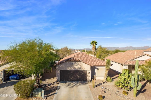 mediterranean / spanish house featuring stucco siding, a tiled roof, a garage, a mountain view, and concrete driveway