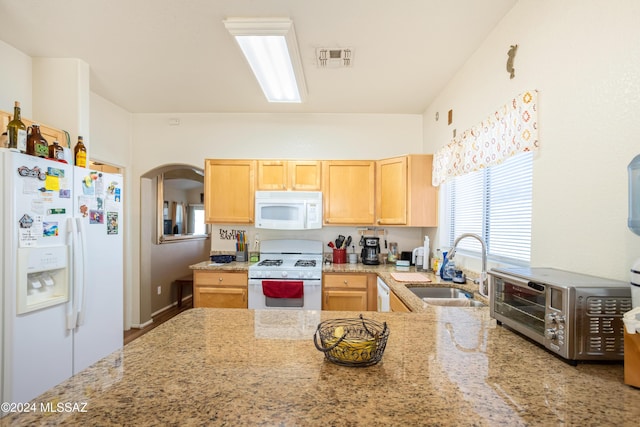 kitchen with a sink, light brown cabinets, light stone counters, white appliances, and a toaster
