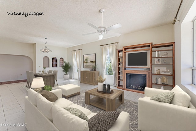 2778 S Via Del Bac, Green Valley, AZ 85622 - living room with light tile patterned floors, a fireplace, a textured ceiling, and ceiling fan with notable chandelier