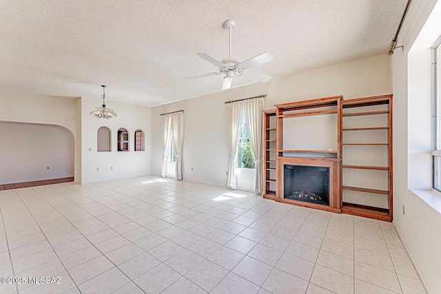 2778 S Via Del Bac, Green Valley, AZ 85622 - unfurnished living room featuring light tile patterned floors, a textured ceiling, ceiling fan with notable chandelier, and a fireplace
