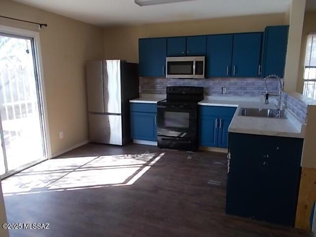 kitchen featuring tasteful backsplash, blue cabinetry, light countertops, appliances with stainless steel finishes, and wood finished floors