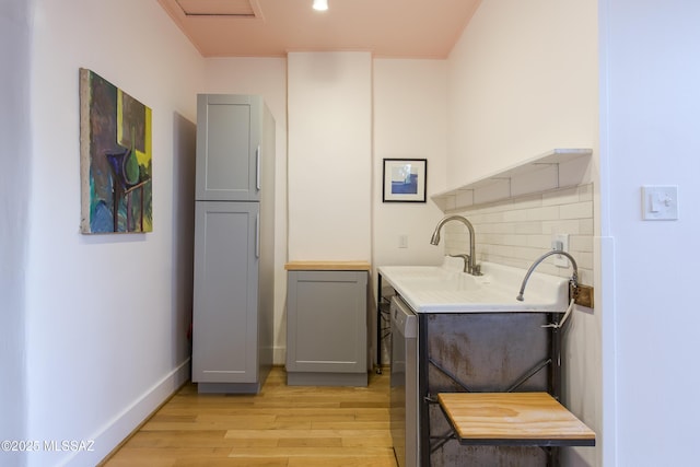 washroom with a sink, light wood-type flooring, and baseboards