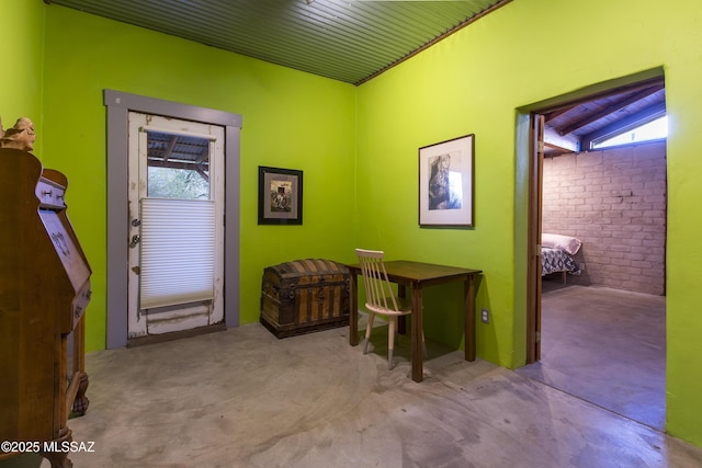 carpeted office featuring a wealth of natural light and brick wall