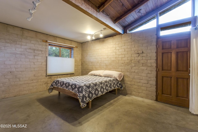 bedroom with track lighting, wooden ceiling, unfinished concrete flooring, and brick wall