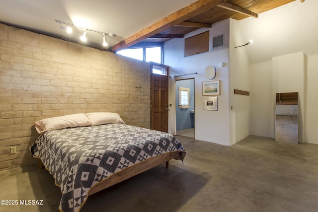 bedroom with visible vents, beam ceiling, a barn door, and brick wall