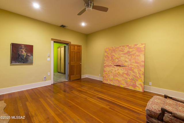 interior space featuring a ceiling fan, visible vents, wood finished floors, and baseboards