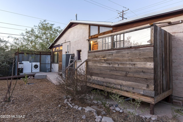 view of home's exterior with fence, stucco siding, and washer and clothes dryer