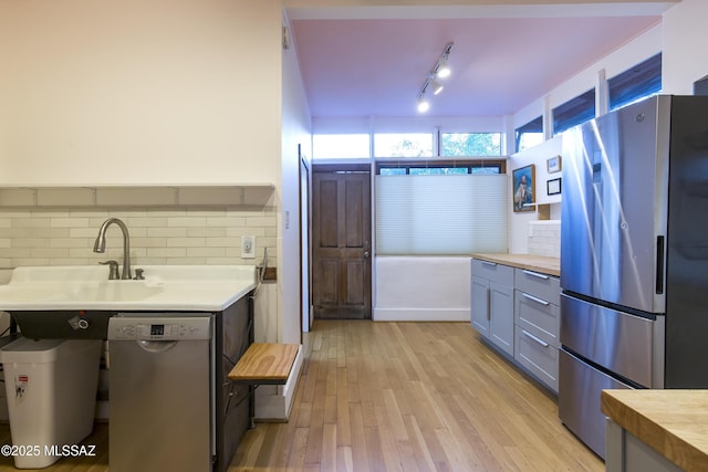 kitchen with decorative backsplash, light wood-style floors, wooden counters, gray cabinetry, and stainless steel appliances