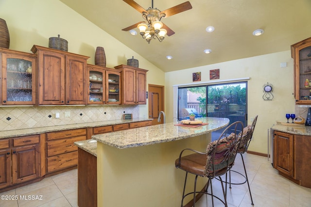 kitchen with light tile patterned flooring, ceiling fan, vaulted ceiling, and tasteful backsplash