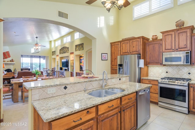 kitchen featuring ceiling fan, visible vents, a sink, a high ceiling, and stainless steel appliances