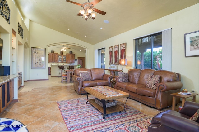 living room featuring arched walkways, ceiling fan, light tile patterned floors, and vaulted ceiling