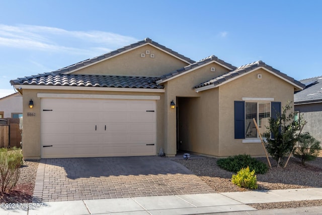 ranch-style house with stucco siding, decorative driveway, a tiled roof, and an attached garage