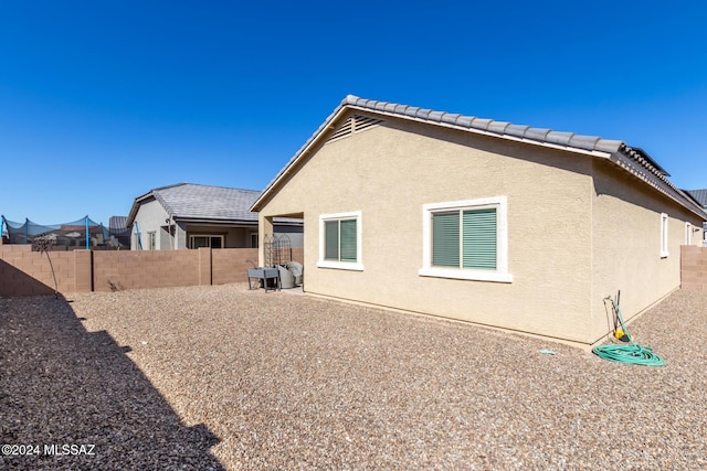 rear view of house featuring a fenced backyard and stucco siding