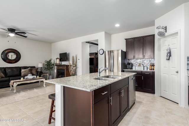 kitchen featuring a sink, ceiling fan, stainless steel appliances, light tile patterned flooring, and open floor plan