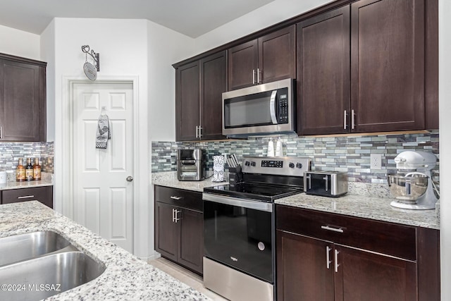 kitchen with tasteful backsplash, light stone countertops, dark brown cabinetry, a toaster, and stainless steel appliances
