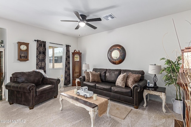 living area with visible vents, a ceiling fan, and light colored carpet