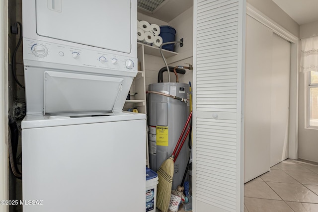 laundry area featuring visible vents, stacked washing maching and dryer, water heater, light tile patterned flooring, and laundry area