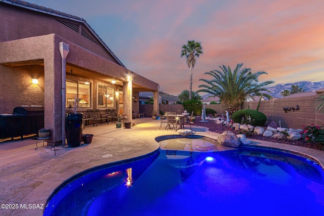 60621 E Eagle Heights Dr, Tucson, AZ 85739 - pool at dusk with a fenced backyard, a fenced in pool, a patio, and outdoor dining area