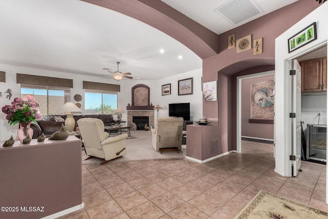 60621 E Eagle Heights Dr, Tucson, AZ 85739 - living room with visible vents, a ceiling fan, a fireplace, baseboards, and arched walkways