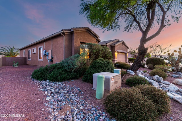 60621 E Eagle Heights Dr, Tucson, AZ 85739 - property exterior at dusk with an attached garage, fence, and stucco siding