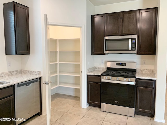 kitchen featuring dark brown cabinetry, light tile patterned flooring, appliances with stainless steel finishes, and light countertops