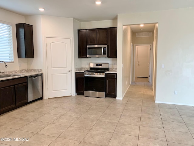 kitchen featuring light tile patterned floors, a sink, appliances with stainless steel finishes, visible vents, and dark brown cabinets