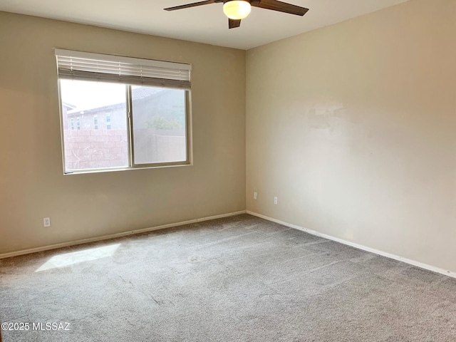 carpeted spare room featuring a ceiling fan and baseboards