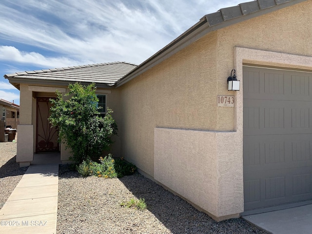 view of home's exterior with a tile roof, a garage, and stucco siding