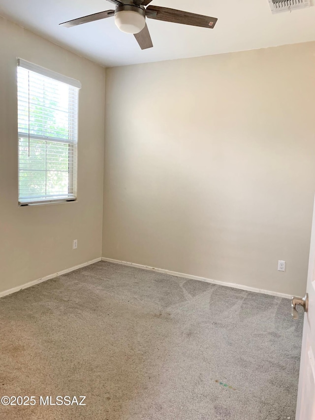 carpeted empty room with a ceiling fan and baseboards