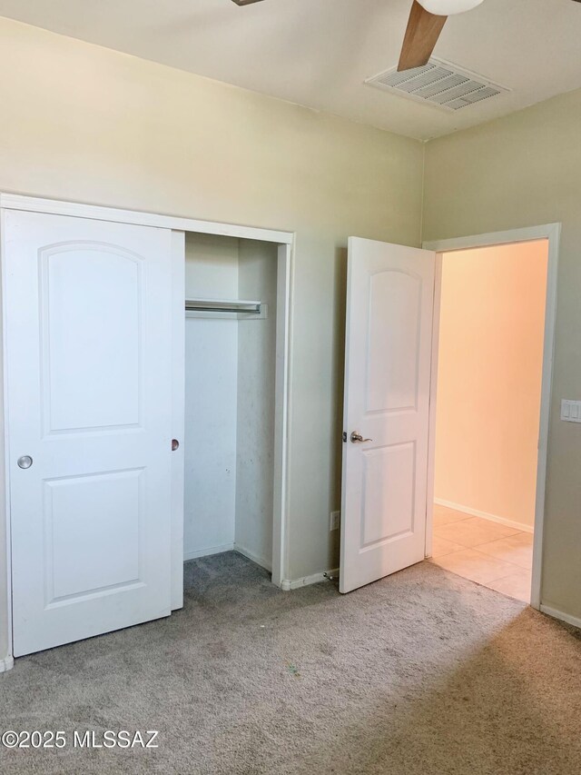 unfurnished bedroom with carpet, visible vents, baseboards, and a closet