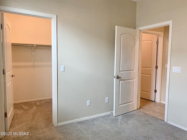 unfurnished bedroom with a walk in closet, carpet floors, and baseboards