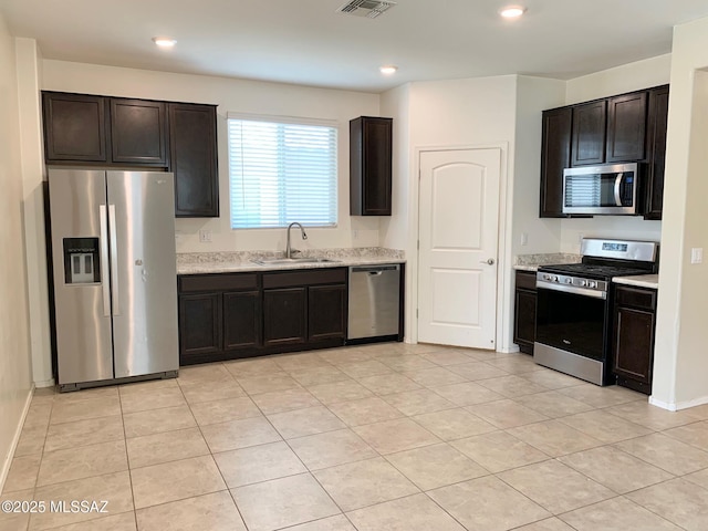 kitchen featuring light tile patterned floors, dark brown cabinetry, stainless steel appliances, and a sink