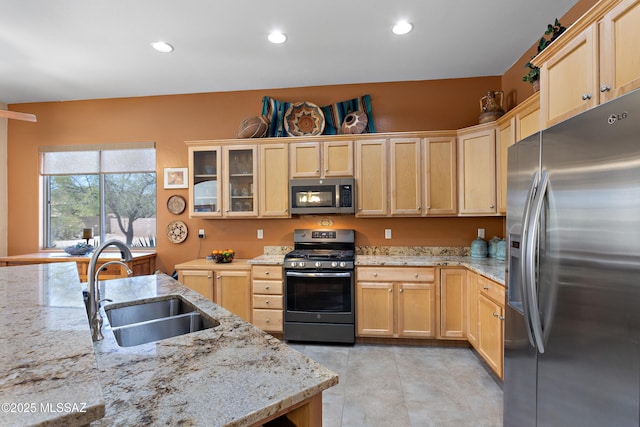 kitchen featuring light brown cabinetry, appliances with stainless steel finishes, a sink, recessed lighting, and glass insert cabinets