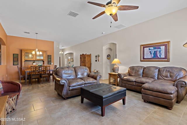 living area with visible vents, arched walkways, and ceiling fan