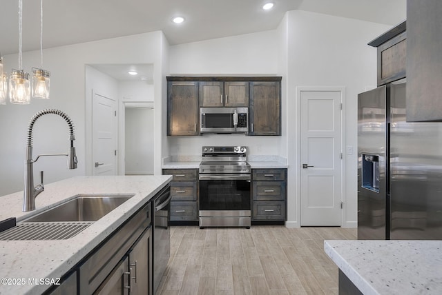 172 Vereda Cabrilla Ln, Rio Rico, AZ 85648 - kitchen with light stone counters, a sink, appliances with stainless steel finishes, dark brown cabinetry, and light wood-type flooring