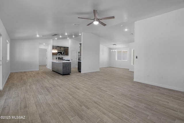 172 Vereda Cabrilla Ln, Rio Rico, AZ 85648 - unfurnished living room featuring baseboards, ceiling fan with notable chandelier, light wood-style flooring, and vaulted ceiling